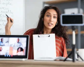 Young woman having video conference using phone and pc
